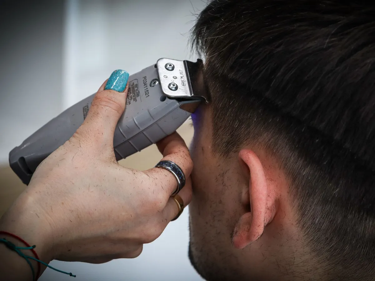 Barbeiro finalizando um corte de cabelo na barbearia